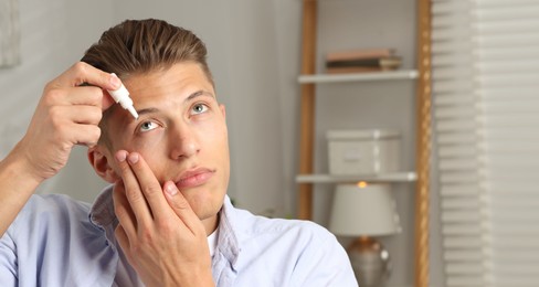 Photo of Young man applying eye drops at home. Space for text