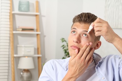 Photo of Young man applying eye drops at home. Space for text