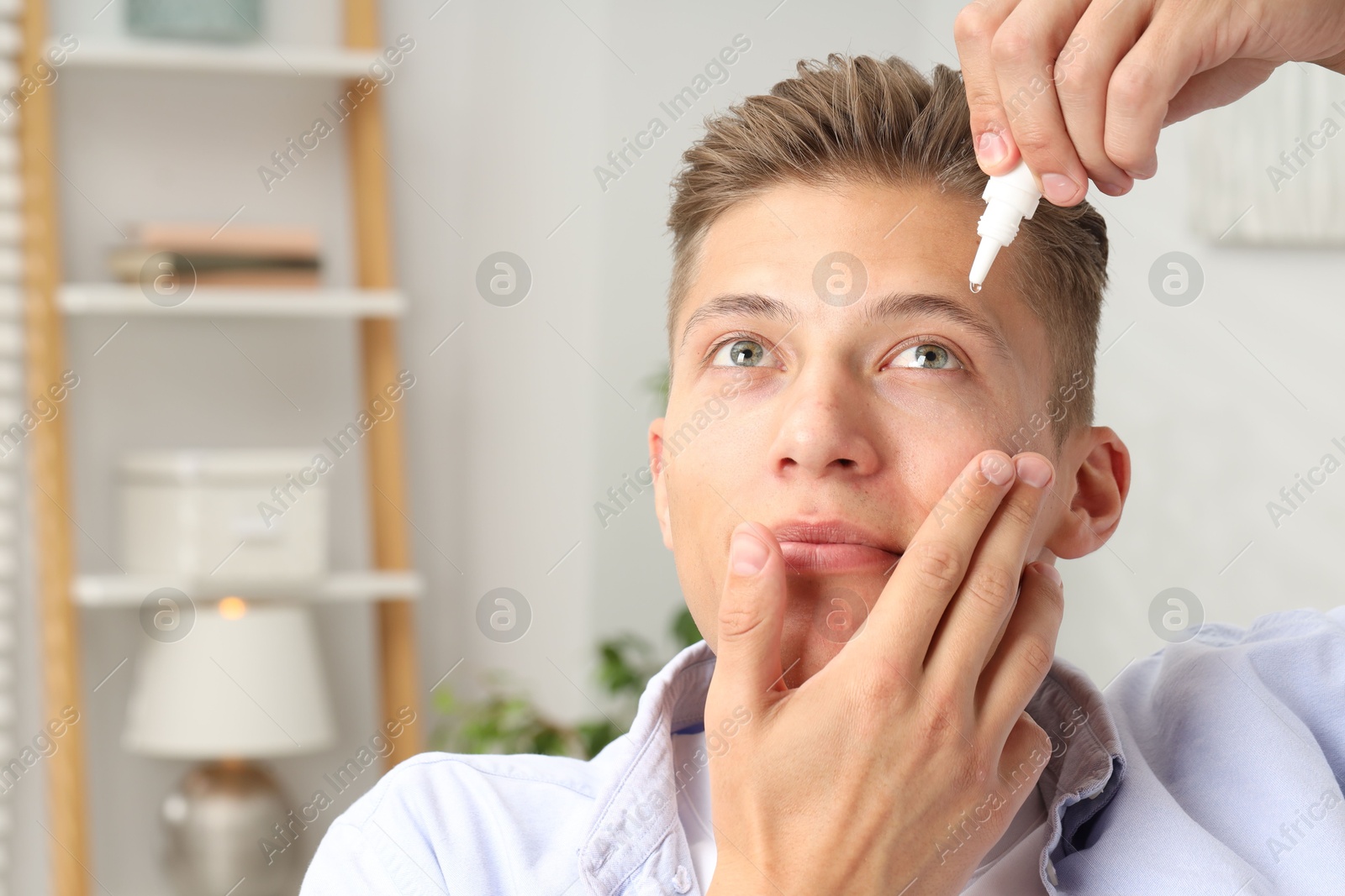 Photo of Young man applying eye drops at home. Space for text