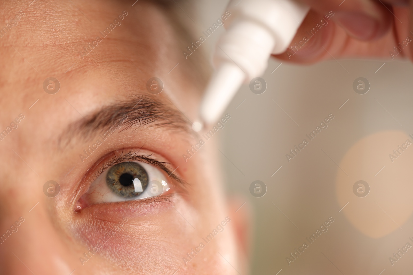 Photo of Man applying eye drops on blurred background, closeup
