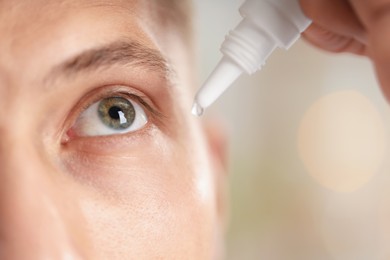 Photo of Man applying eye drops on blurred background, closeup