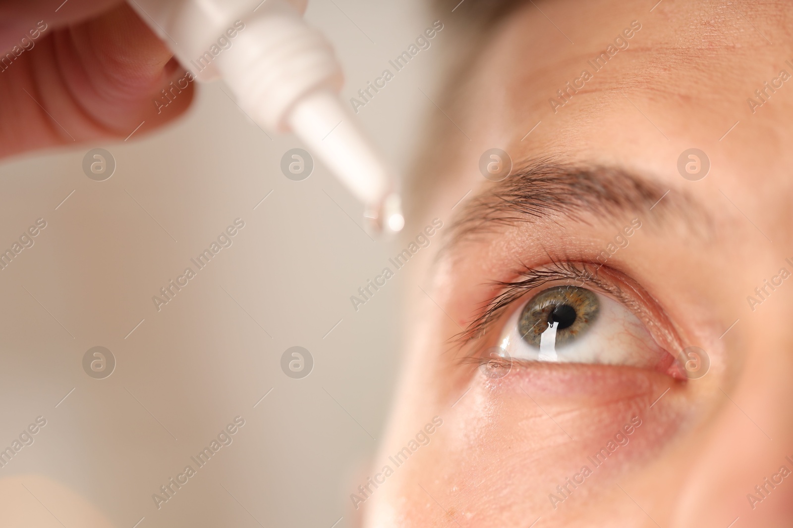 Photo of Man applying eye drops on blurred background, closeup