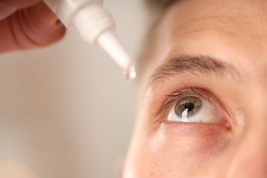 Photo of Man applying eye drops on blurred background, closeup