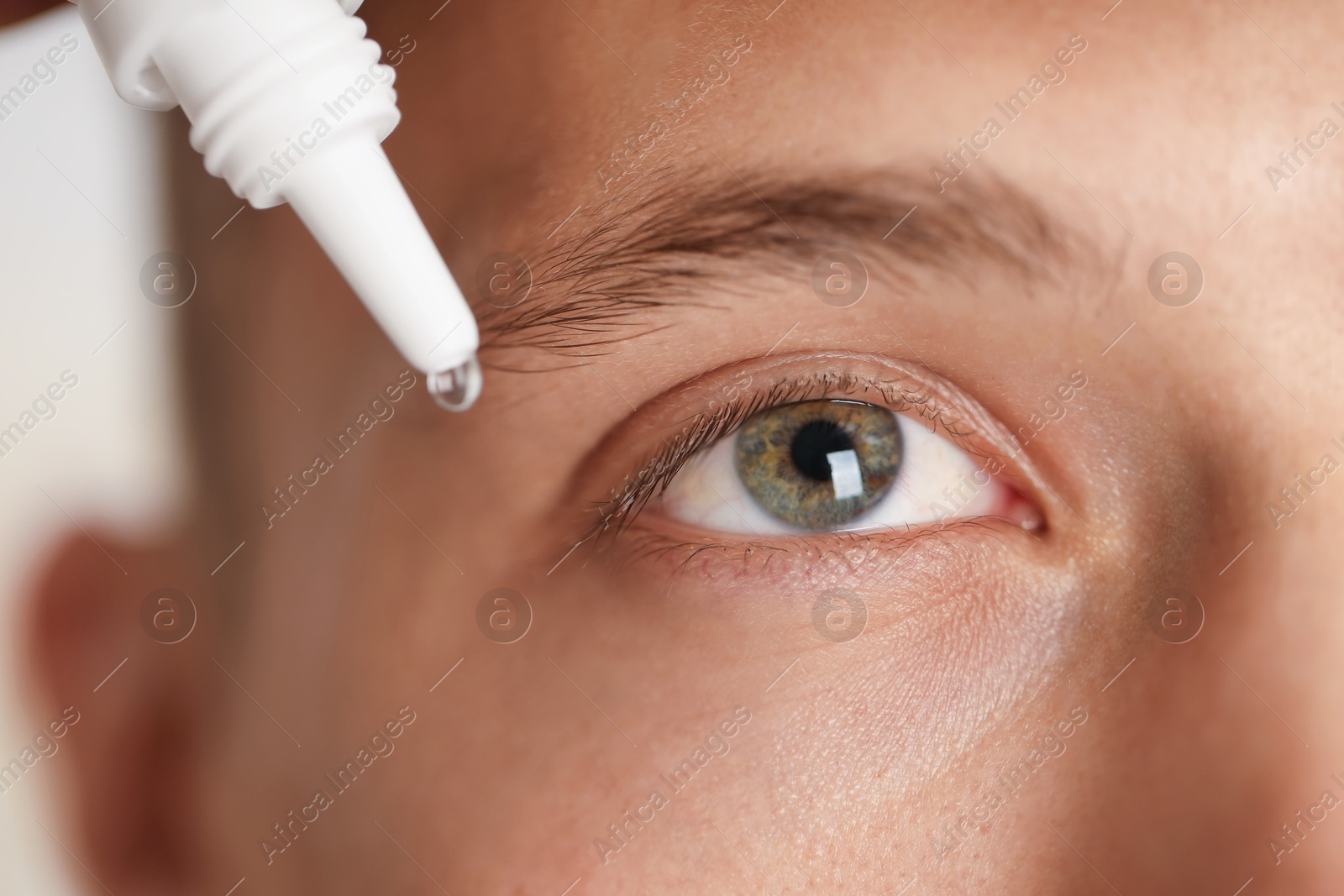 Photo of Man applying eye drops on light background, closeup