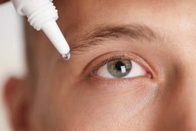 Photo of Man applying eye drops on light background, closeup