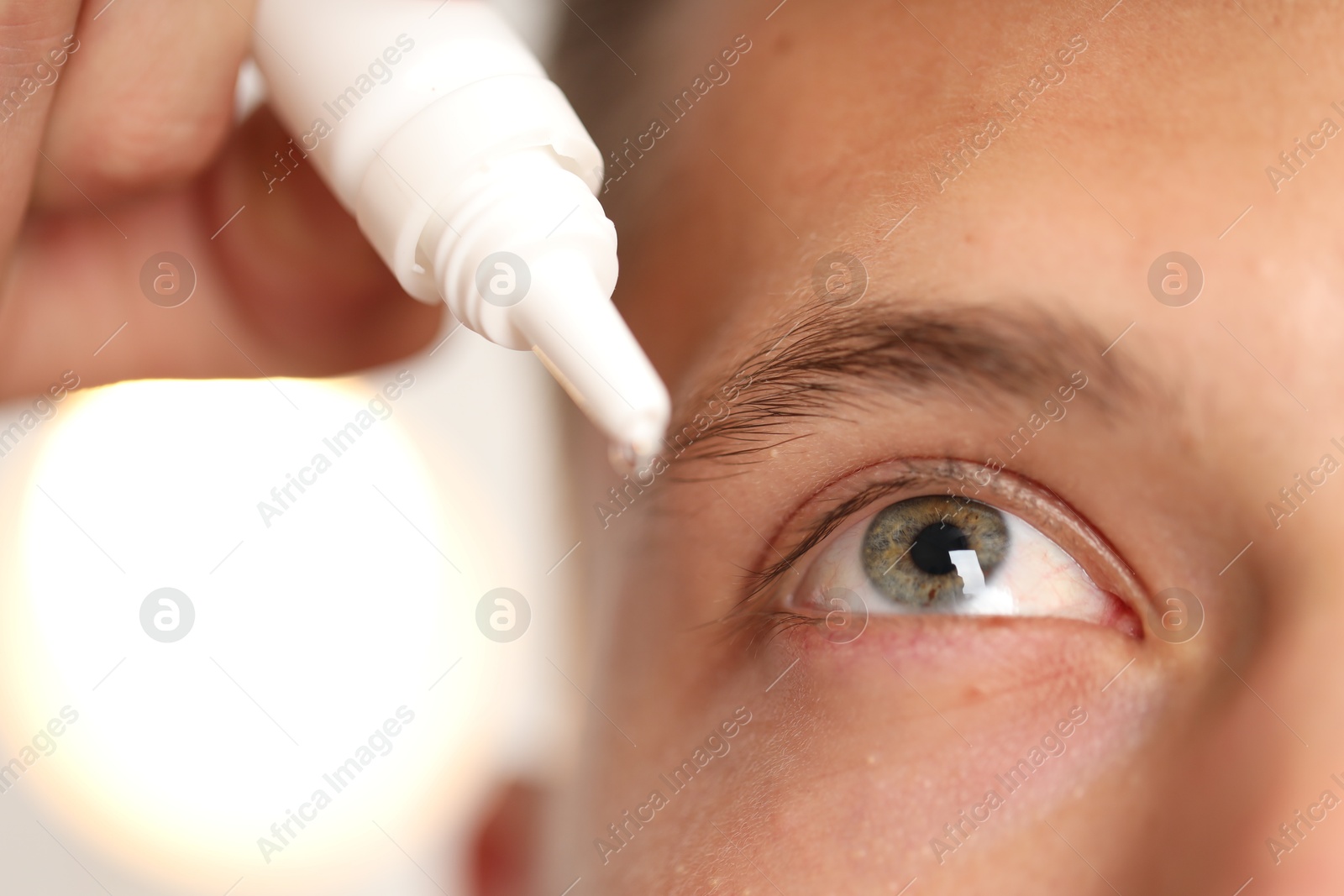Photo of Man applying eye drops on light background, closeup