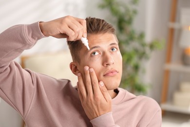 Photo of Young man applying eye drops at home
