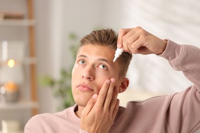 Photo of Young man applying eye drops at home