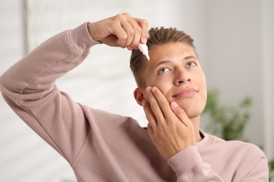 Photo of Young man applying eye drops at home