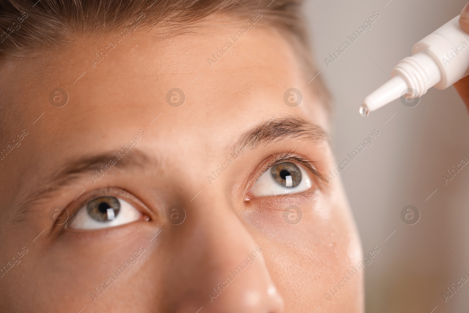 Photo of Man applying eye drops on blurred background, closeup