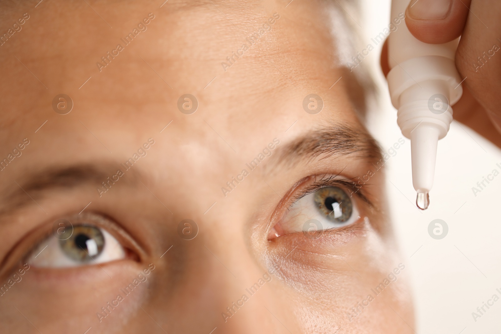 Photo of Man applying eye drops on light background, closeup