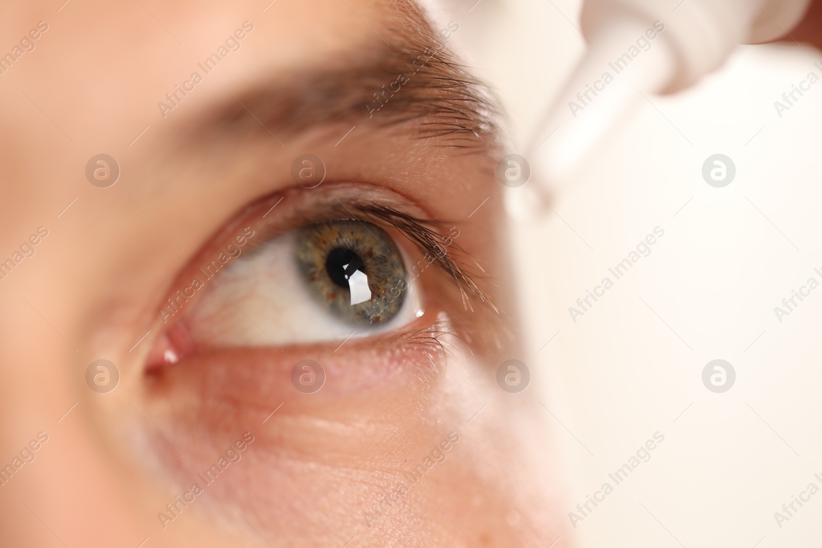 Photo of Man applying eye drops on light background, closeup