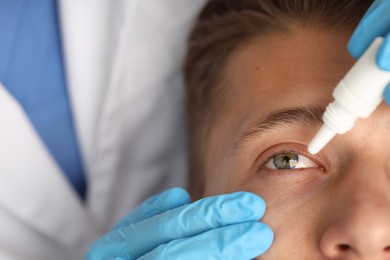 Photo of Doctor putting drops into man's eye, closeup