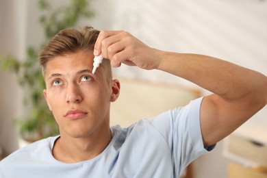 Photo of Young man applying eye drops at home
