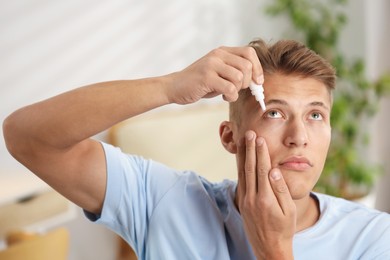 Photo of Young man applying eye drops at home