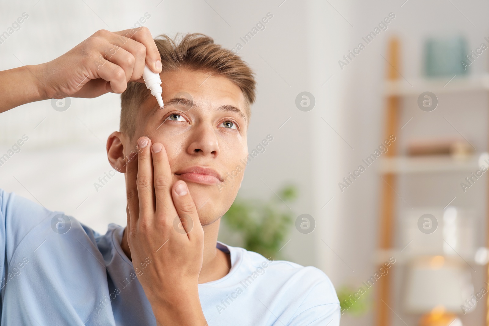 Photo of Young man applying eye drops at home. Space for text