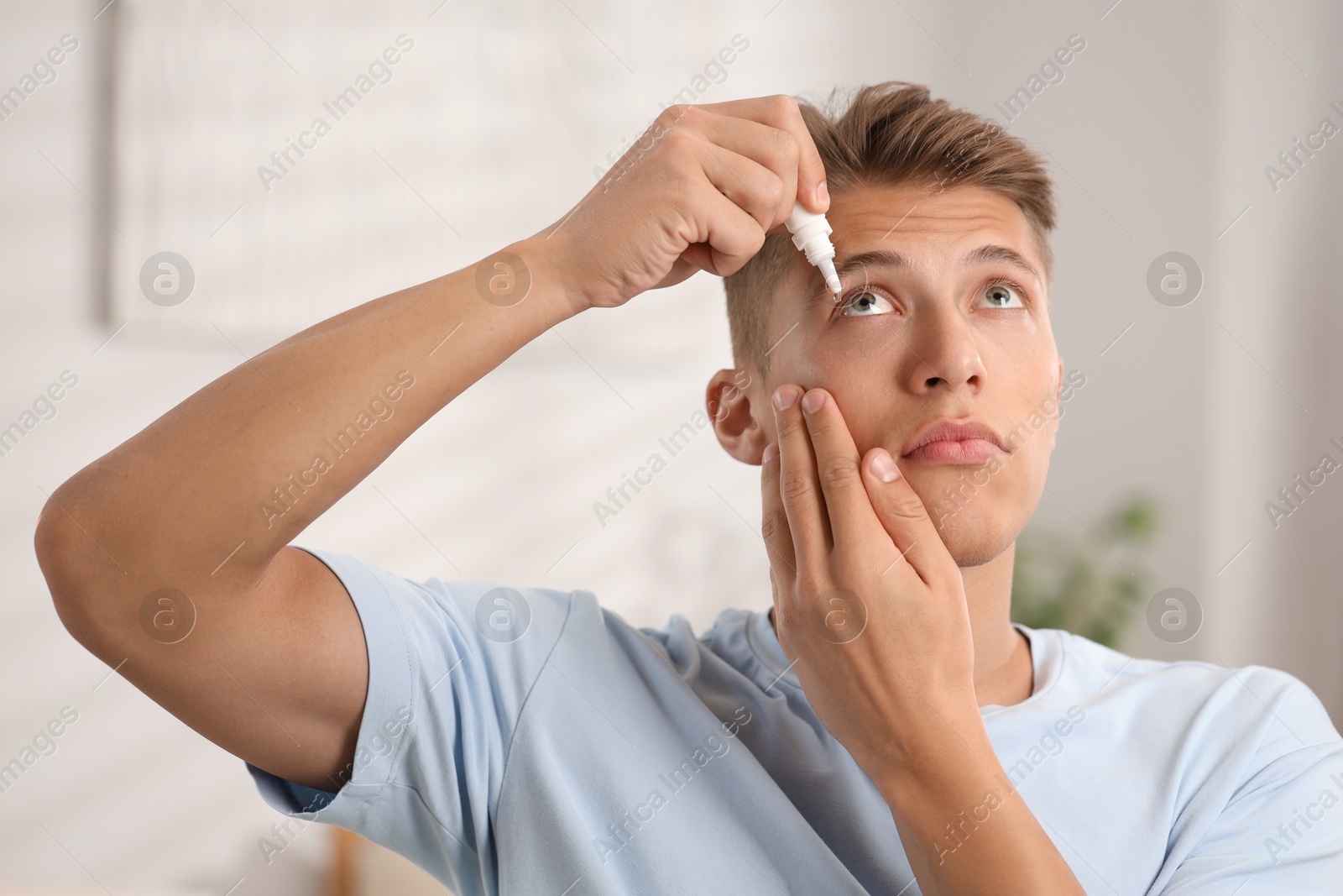 Photo of Young man applying eye drops at home