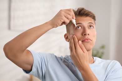 Photo of Young man applying eye drops at home