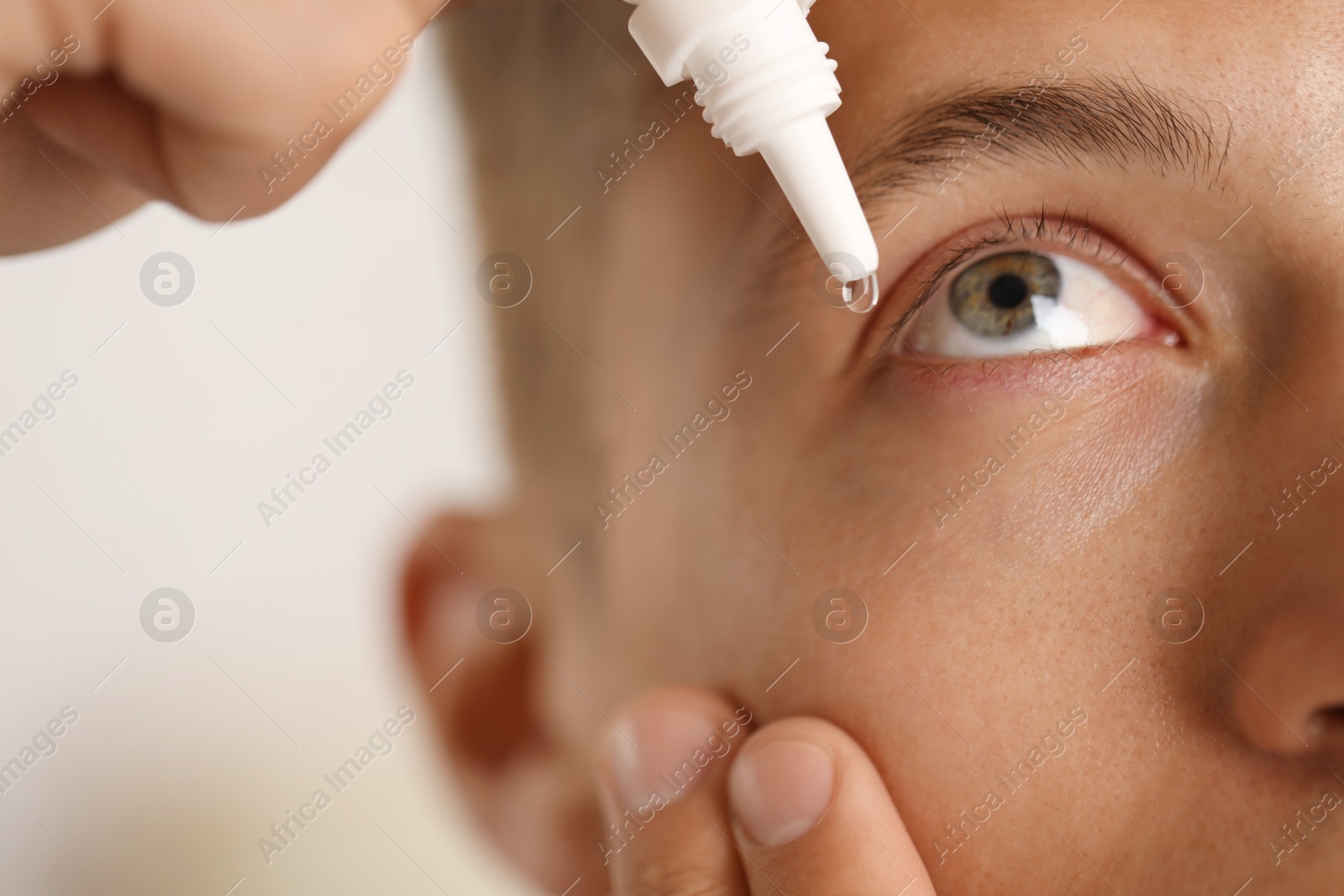 Photo of Man applying eye drops on light background, closeup