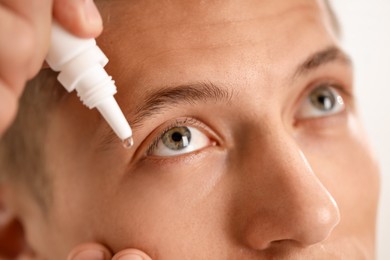 Photo of Man applying eye drops on light background, closeup