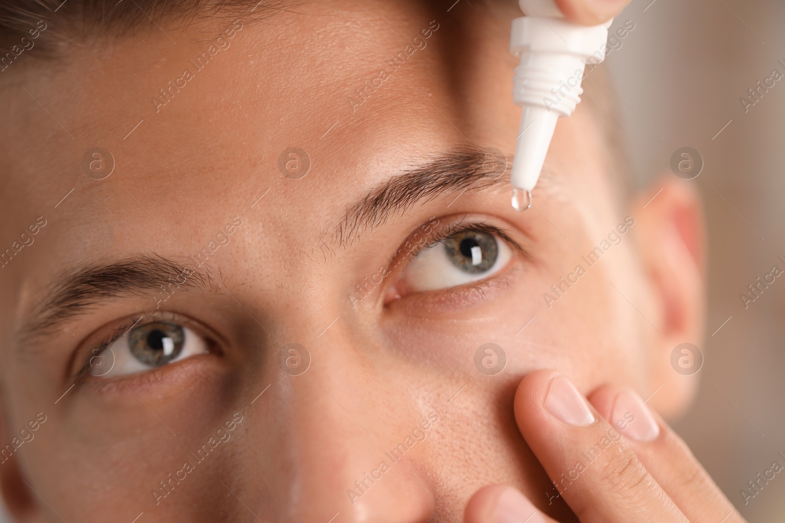 Photo of Man applying eye drops on blurred background, closeup