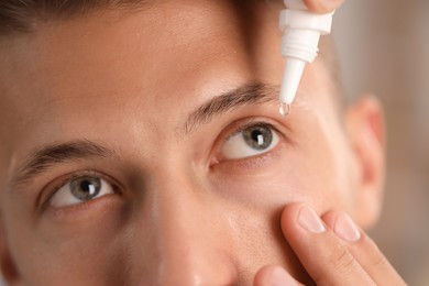 Photo of Man applying eye drops on blurred background, closeup