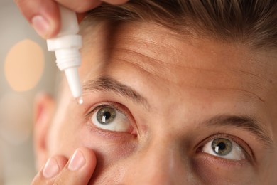 Photo of Man applying eye drops on blurred background, closeup