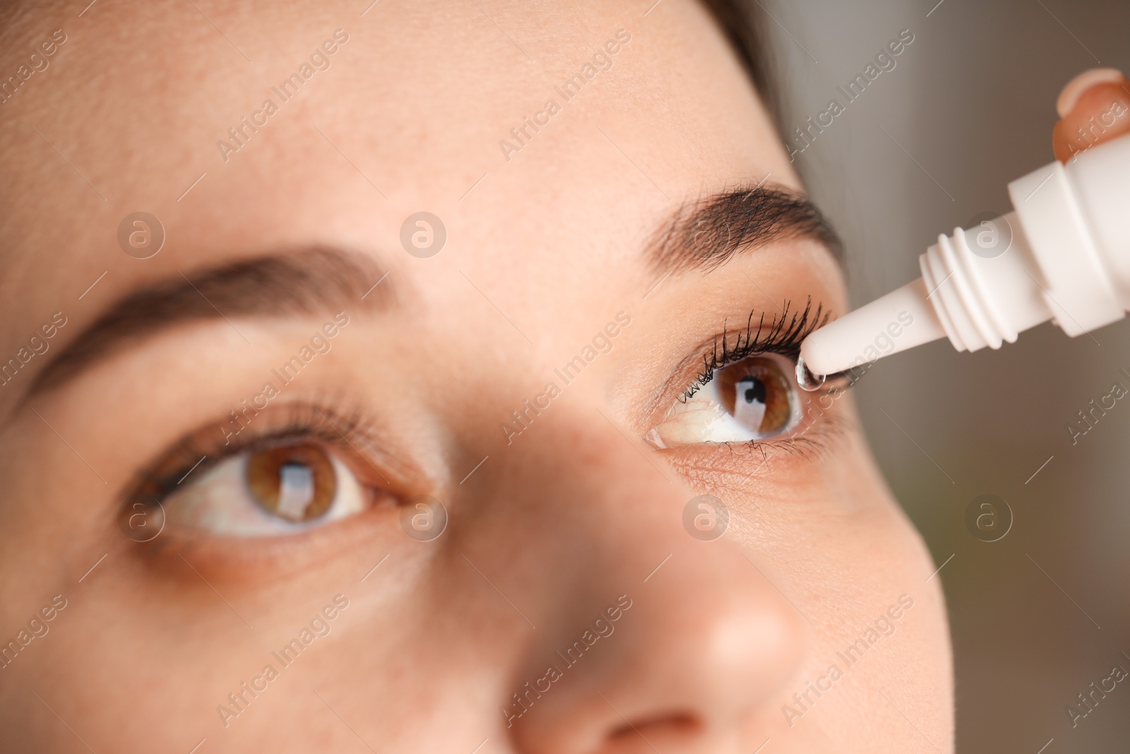 Photo of Woman applying eye drops on blurred background, closeup