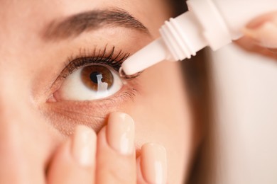 Photo of Woman applying eye drops on blurred background, closeup
