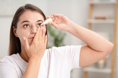 Photo of Young woman applying eye drops at home