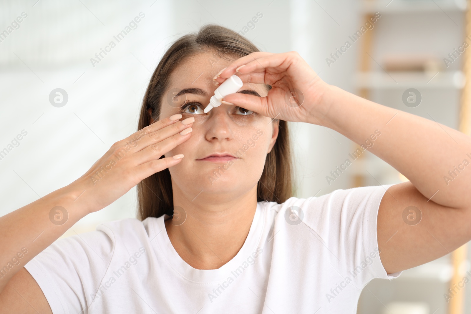 Photo of Young woman applying eye drops at home