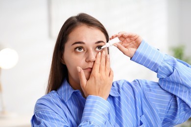 Photo of Young woman applying eye drops at home