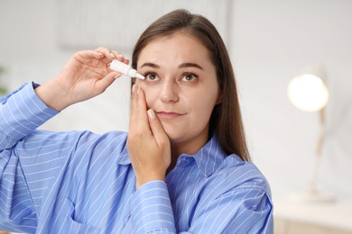 Photo of Young woman applying eye drops at home