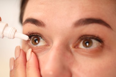 Photo of Woman applying eye drops on blurred background, closeup