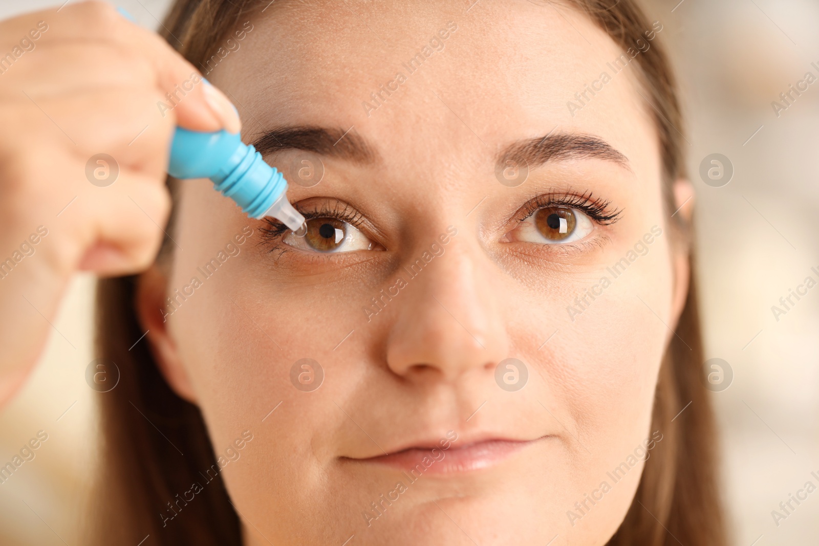 Photo of Woman applying eye drops on blurred background, closeup