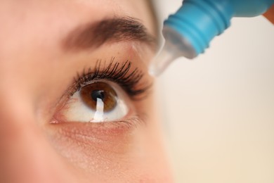 Photo of Woman applying eye drops on blurred background, closeup