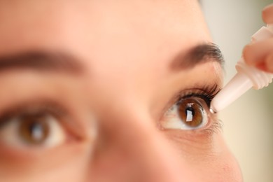 Photo of Woman applying eye drops on blurred background, closeup