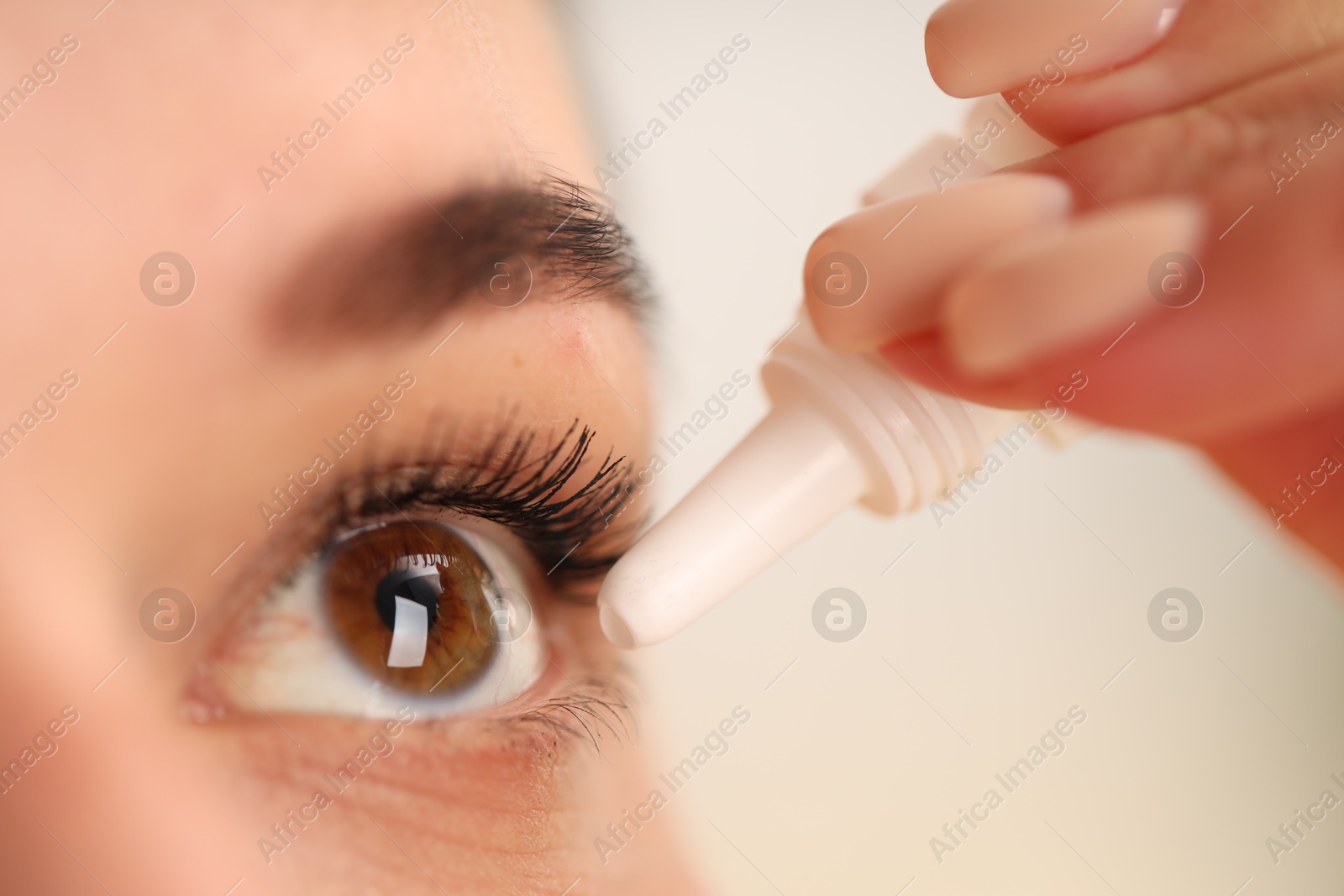 Photo of Woman applying eye drops on blurred background, closeup