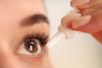 Photo of Woman applying eye drops on blurred background, closeup