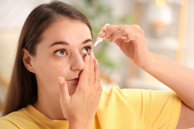 Photo of Young woman applying eye drops at home