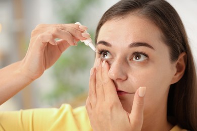 Photo of Young woman applying eye drops at home