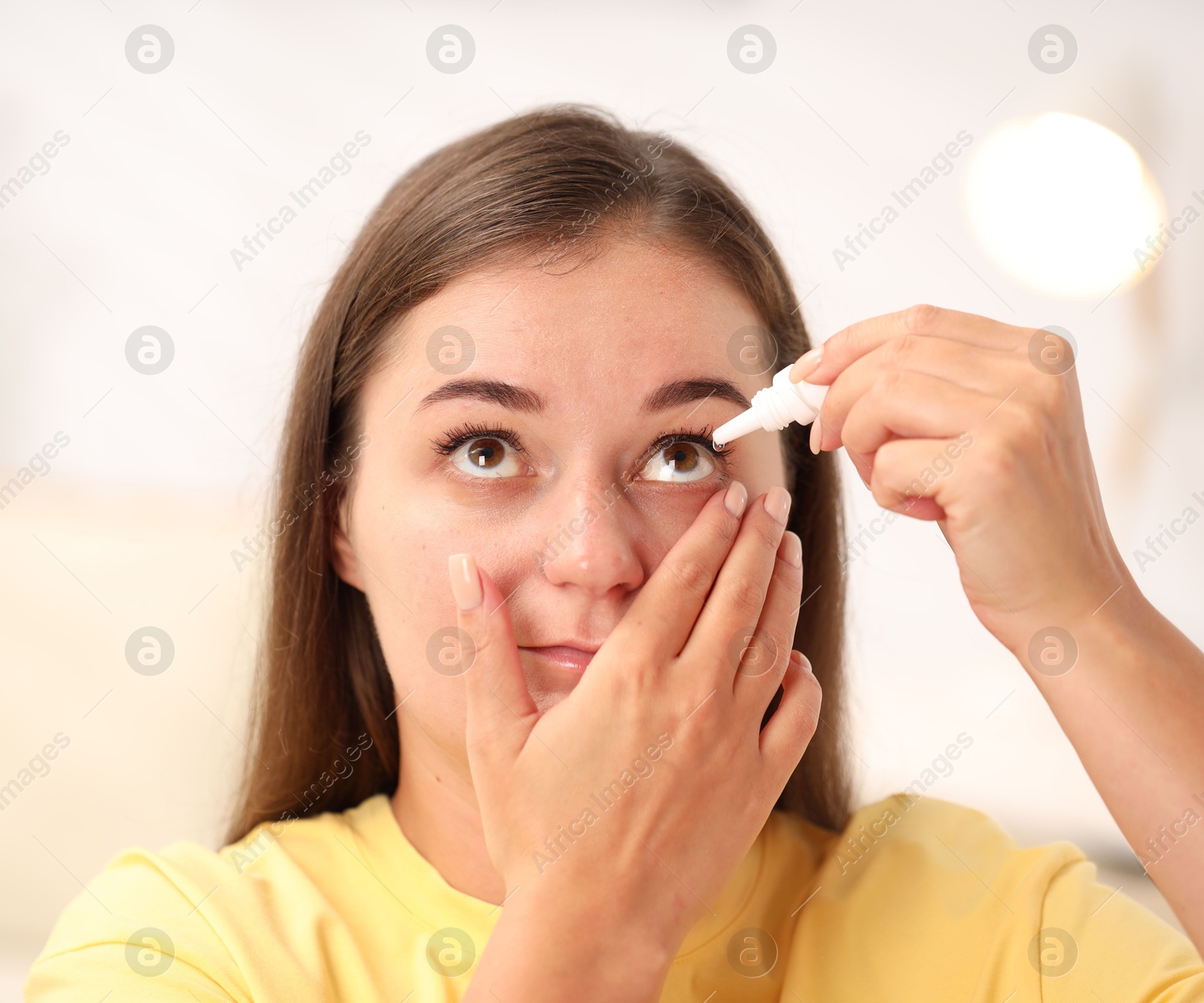 Photo of Young woman applying eye drops at home