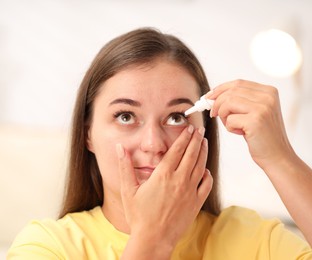 Photo of Young woman applying eye drops at home