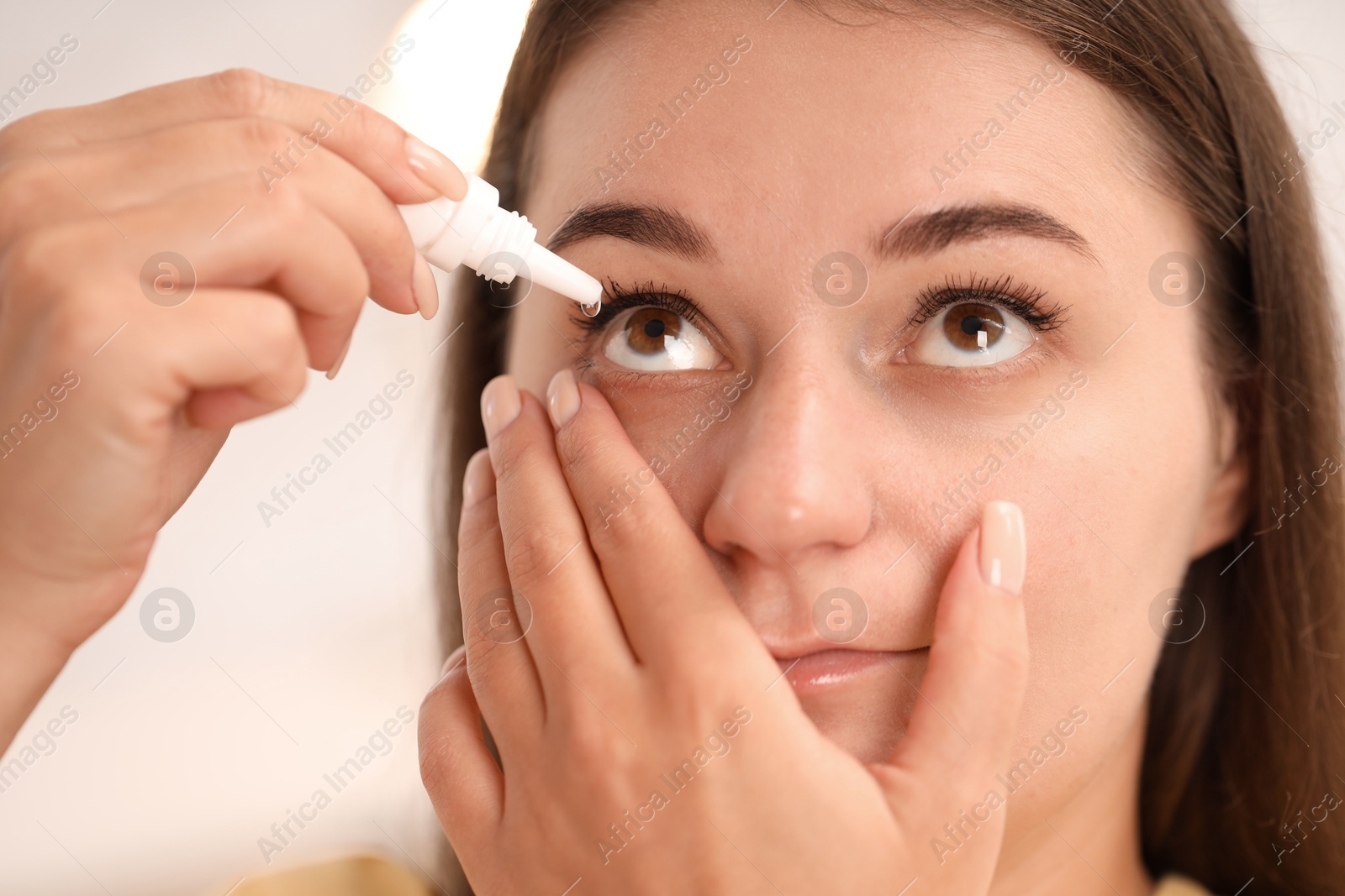 Photo of Woman applying eye drops on blurred background, closeup