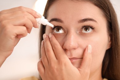 Photo of Woman applying eye drops on blurred background, closeup