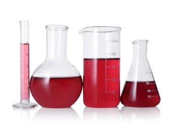 Photo of Different laboratory glassware with red liquid isolated on white