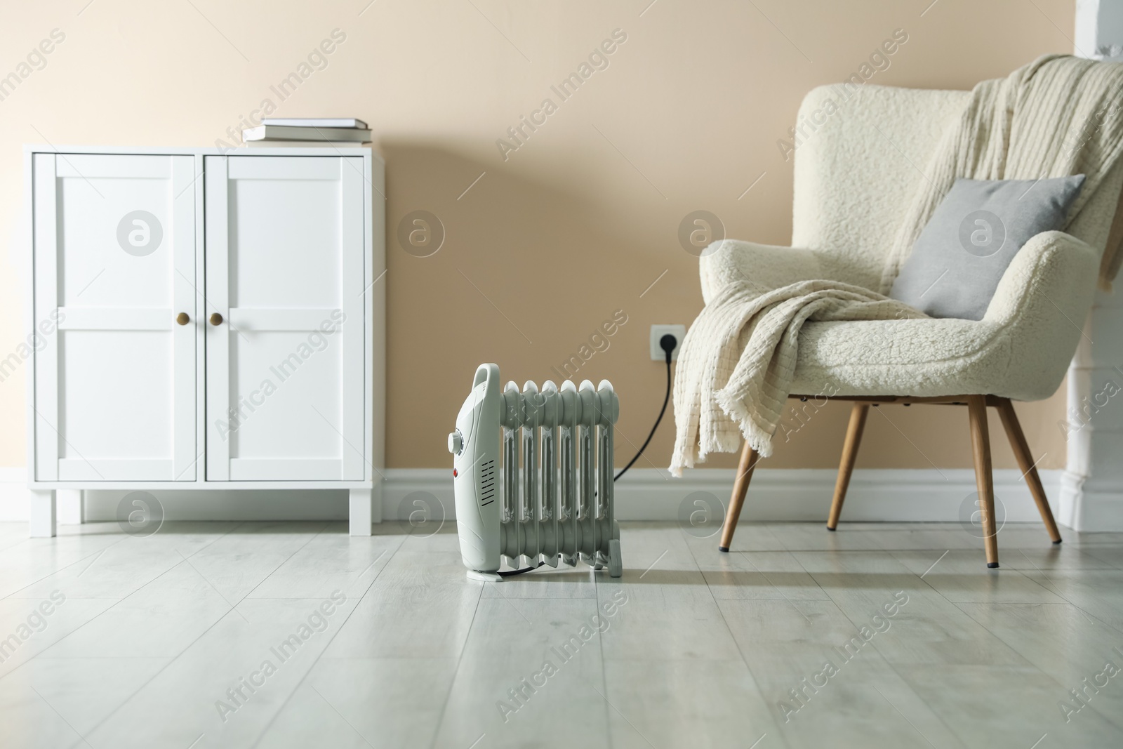 Photo of Electric heater on light wooden floor indoors