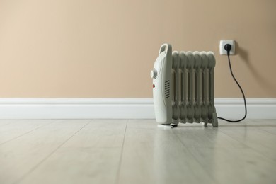 Photo of Electric heater on floor near beige wall indoors. Space for text