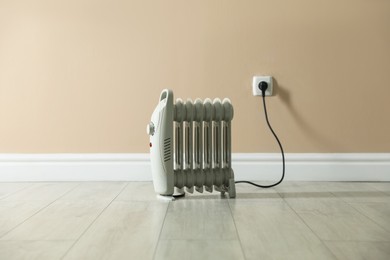 Photo of Electric heater on floor near beige wall indoors