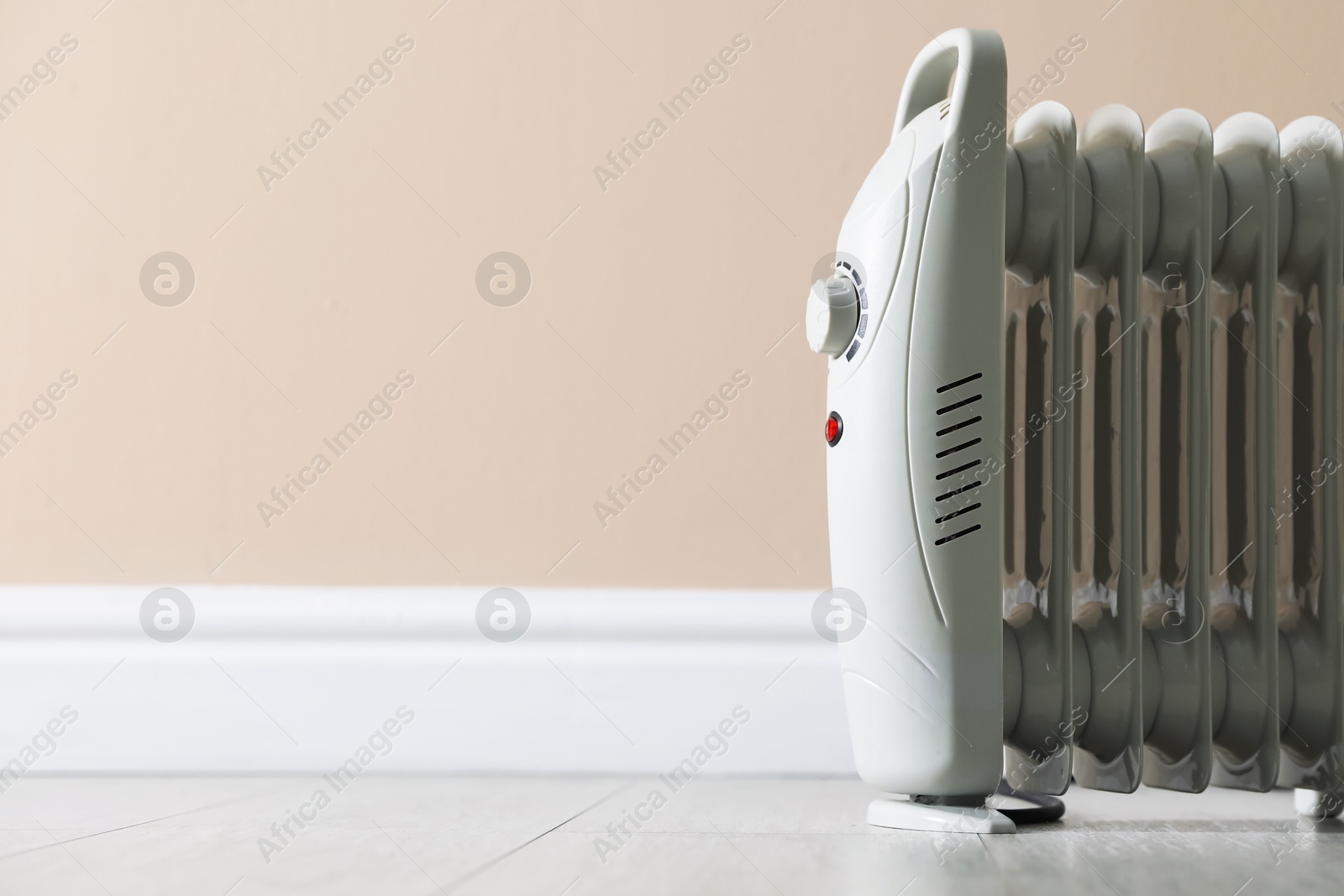 Photo of Electric heater on floor near beige wall indoors, closeup. Space for text